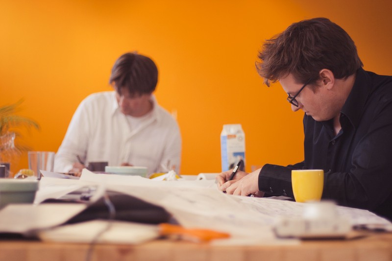 Two professionals collaborate at a table during a brainstorming session focused on design and project planning.