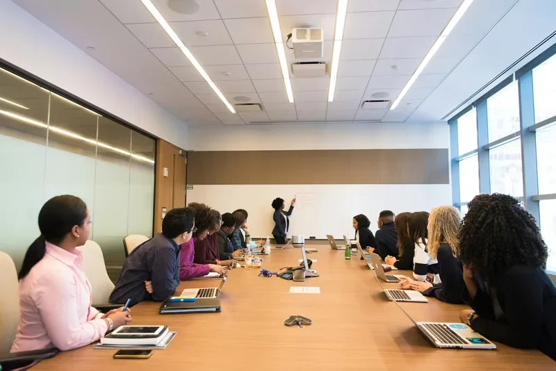 Executive boardroom meeting with professionals reviewing documents and presentations