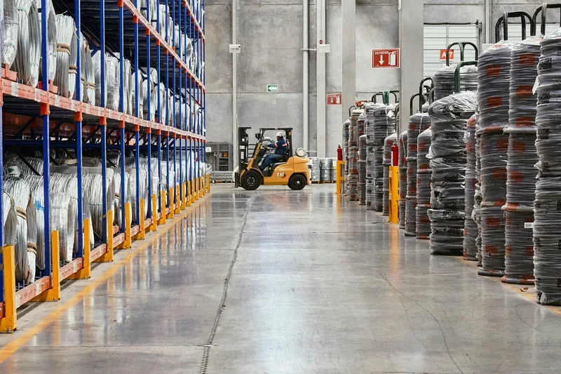 Forklift operating in industrial warehouse with stacked goods, illustrating supply chain logistics complexity